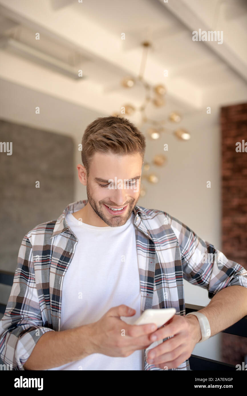 Schöner Mann lächelnd beim Lesen der Nachricht von der Freundin Stockfoto