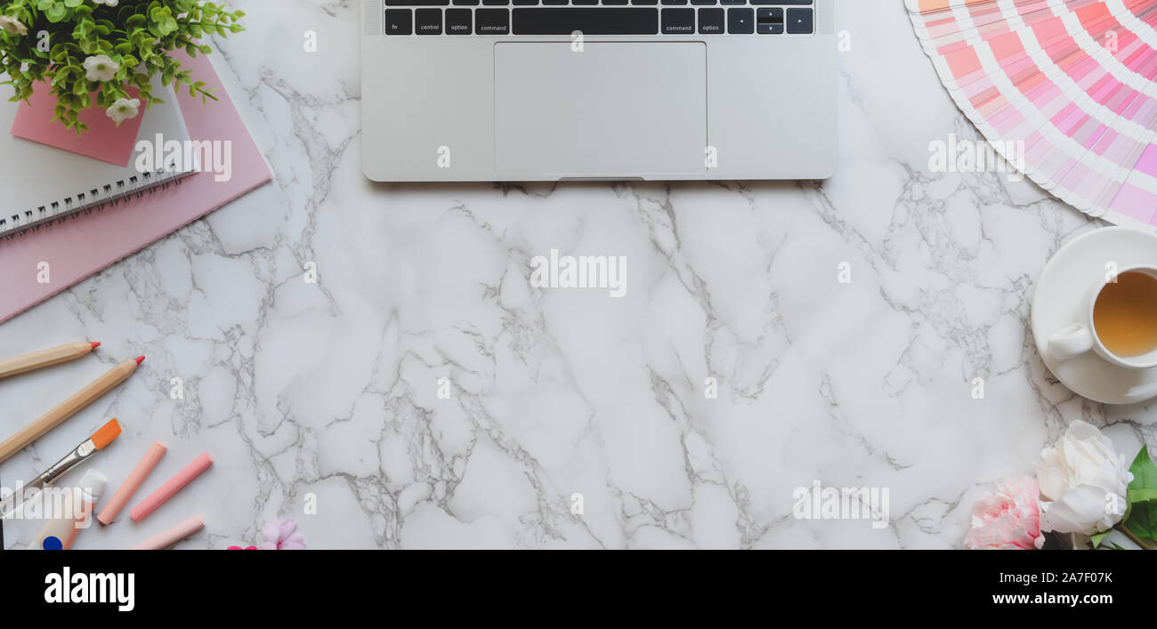Blick von oben auf die rosa feminin Designer Arbeitsbereich mit Laptop und Malwerkzeuge auf Marmor Schreibtisch Hintergrund Stockfoto