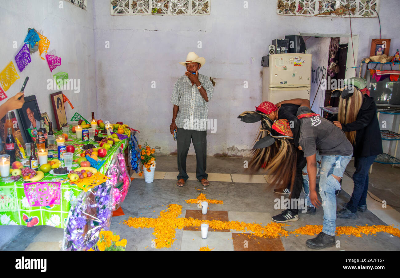 01 November 2019, Mexiko, Cuajinicuilapa: Musiker (M) spielt die Oberschwingungen, während die drei Männer, die als Teufel Tanz Vor einem Altar von einem toten Mann verkleidet. Sie glauben, dass die Seelen der Verstorbenen wird durch den Tanz zurück mit ihren Familien auf den Tag der Toten wieder zu vereinen. Wie jedes Jahr, die Städte der Costa Chica von Guerrero, im Süden von Mexiko, feiern die Toten mit dem Tanz von ihren Vorfahren afrikanischer Herkunft geerbt. Der Tanz der Teufel, Choreographie, mit der Sie springen und stomp durch die Straßen von Cuajinicuilapa und die Seelen der Toten ins th bringen Stockfoto