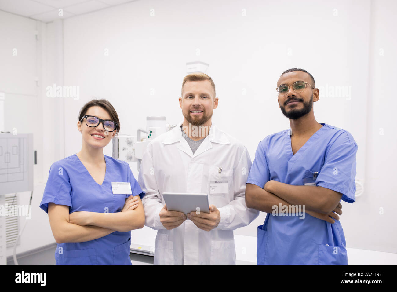 Gruppe von drei junge erfolgreiche interkulturelle Kliniker oder Praktikanten in Uniform Stockfoto