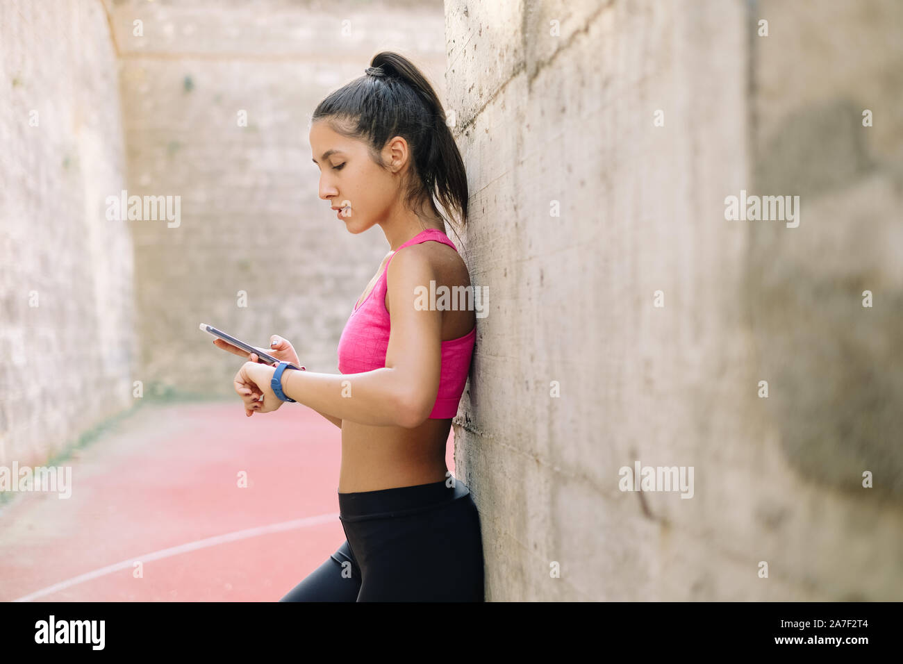 Mädchen Abgleich von Daten aus Fitness Tracker in einem Smartphone App Stockfoto
