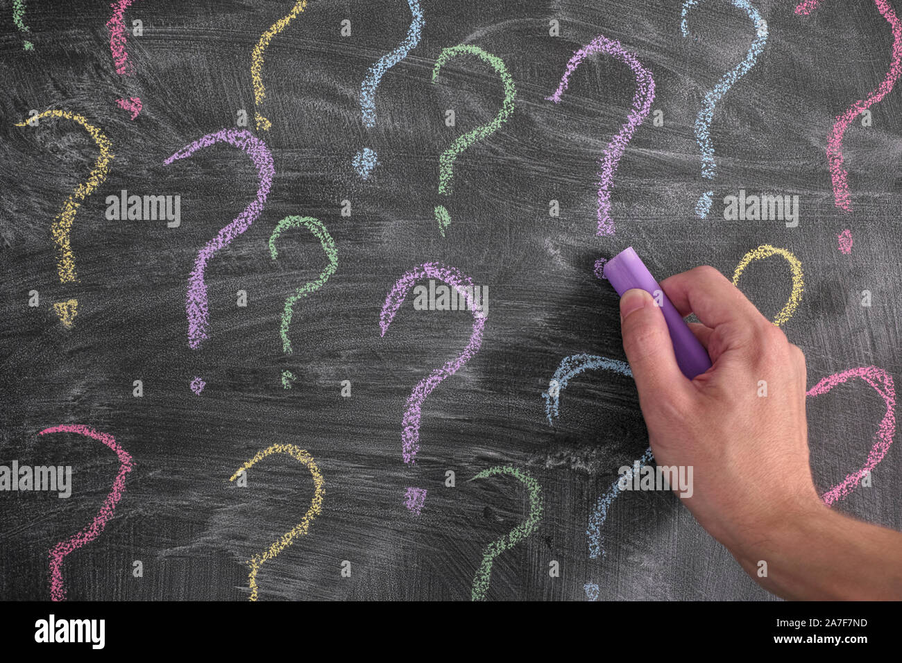 Mann Zeichnung bunte Fragezeichen auf Tafel. Close Up. Stockfoto