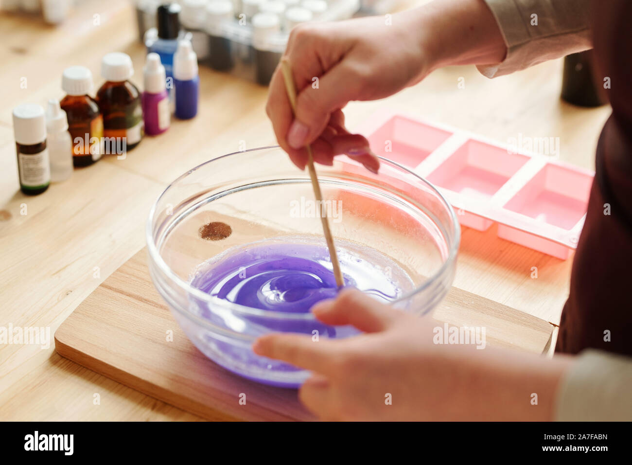 Hände von kreativen Mädchen mischen Lavendel Farbe mit flüssiger Seife Masse in Gläser Stockfoto