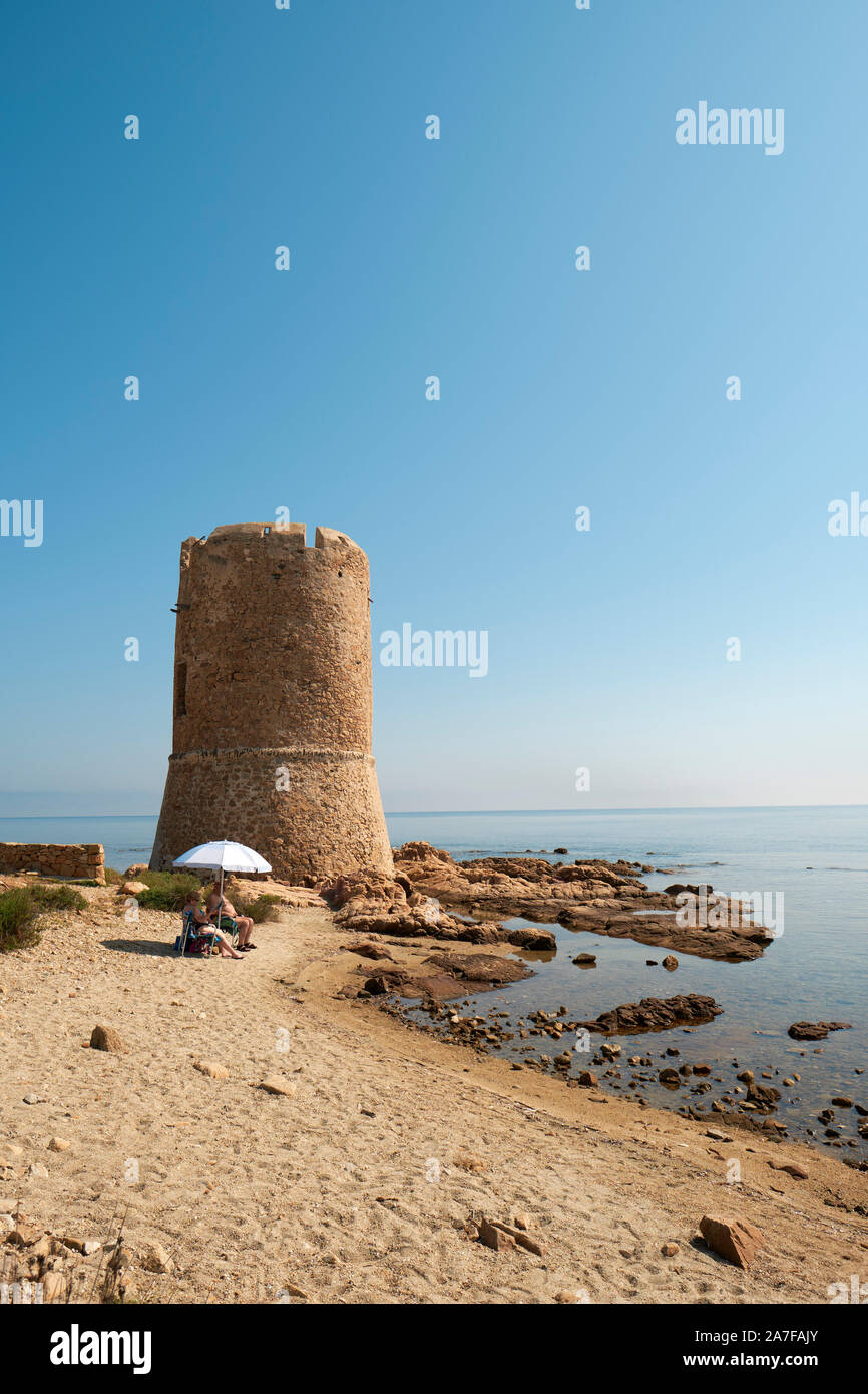 Eine kleine Sommer Strand mit Sonnenschirm und der Torre di San Giovanni Wachturm auf der sardischen Küste bei La Caletta in Nuoro Sardinien Italien Europa Stockfoto