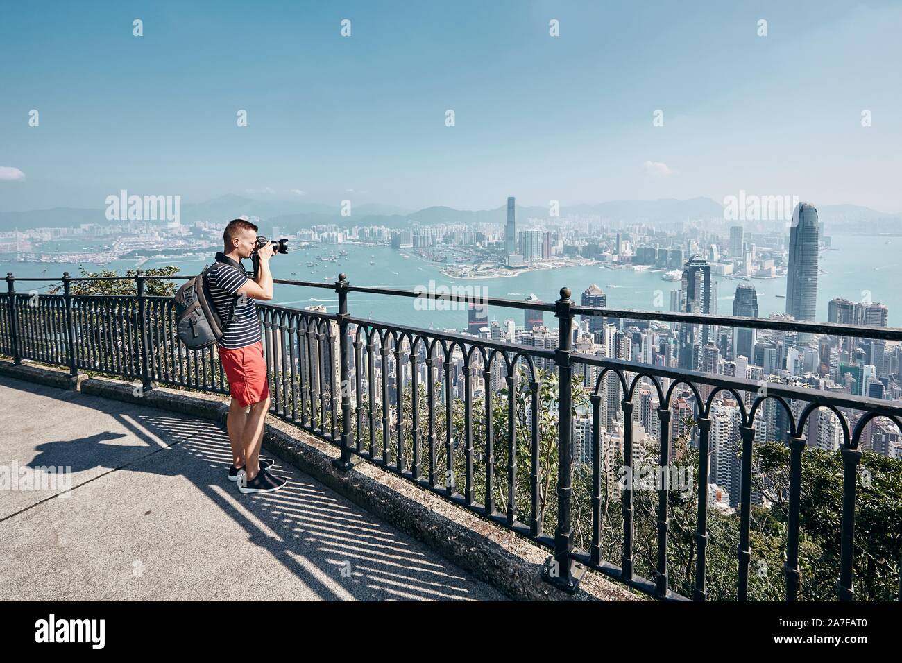Junger Mann (Reisender) mit Rucksack fotografieren städtischen Skyline. Victoria Peak, Hong Kong. Stockfoto