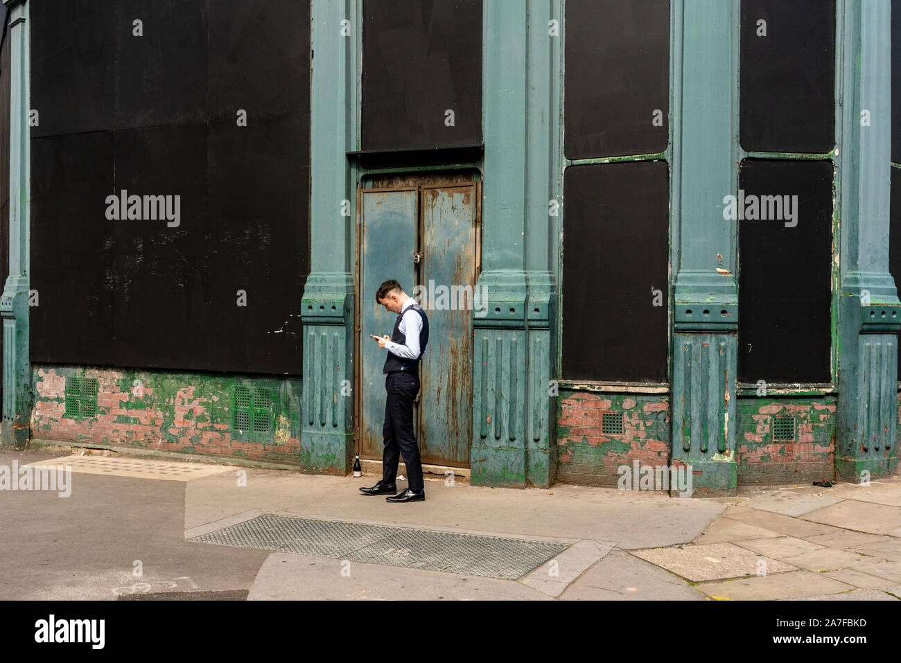 Geschäftsmann mit seinem Smart Phone in der Jetzt aufgegebenen Smithfield Market in London, Großbritannien Stockfoto