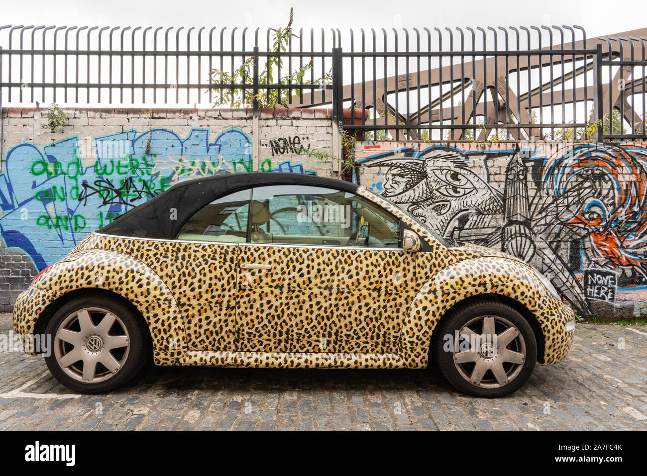 Ein leopard Haut drucken livered VW Käfer auf einem Shoreditch zurück Street direkt an der Brick Lane, East London, Großbritannien Stockfoto