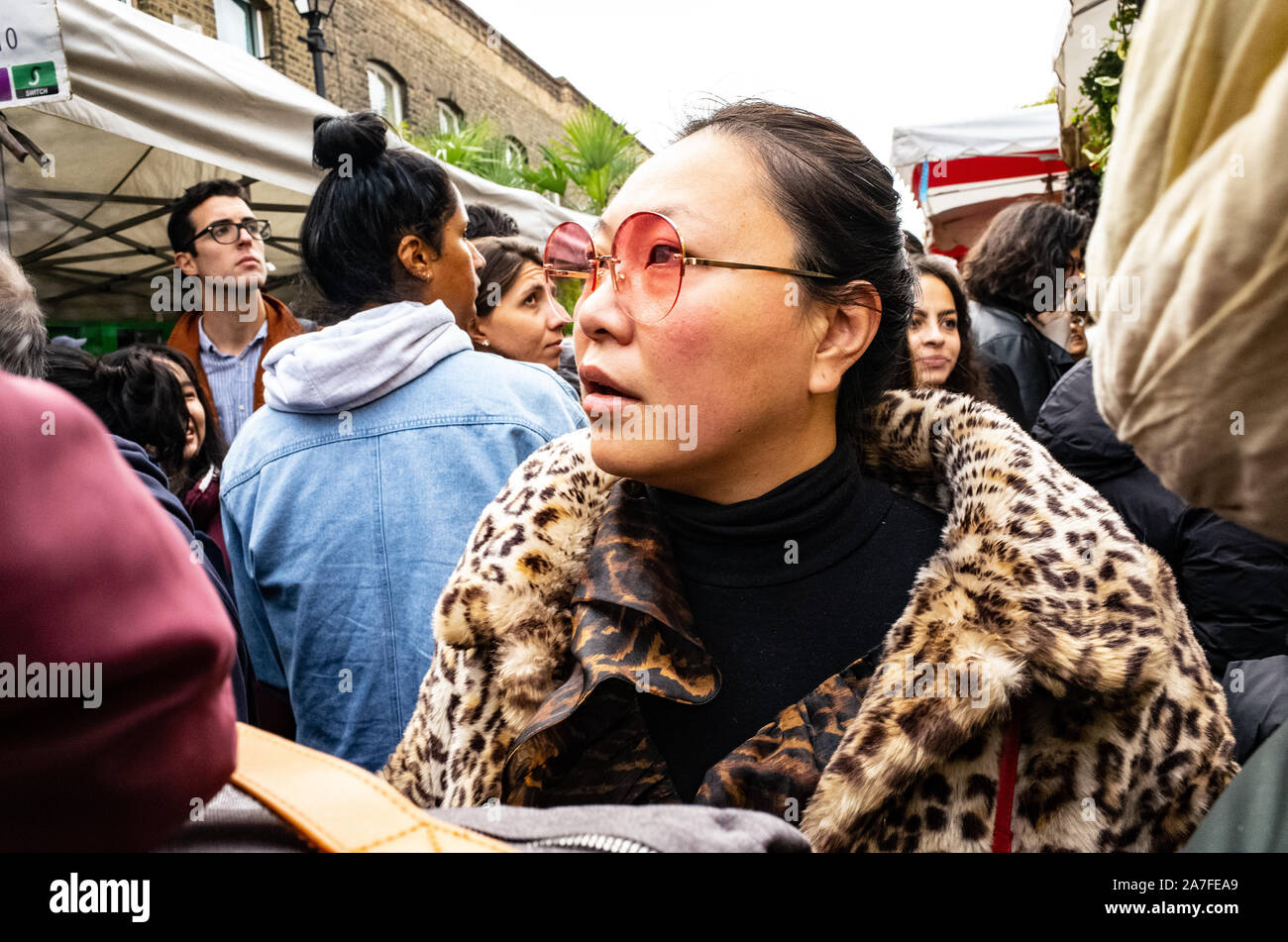 Asiatische Dame im Leopardenmuster Fell einkaufen bei Columbia Road Blumenmarkt, East London, Großbritannien Stockfoto