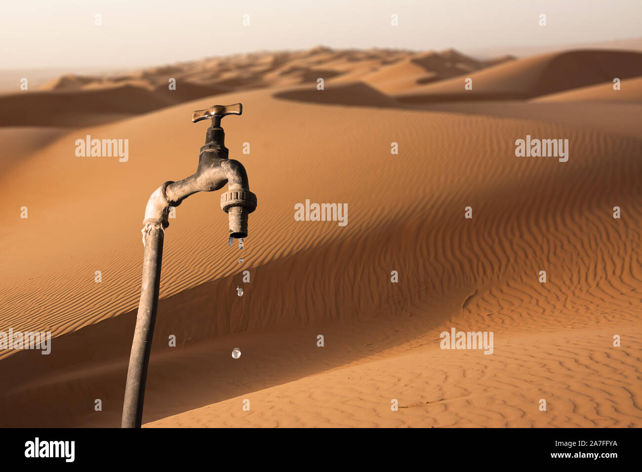 Tropfenden Hahn und Umwelt Wüste im Hintergrund, Konzept der Austrocknung des Planeten und Wasserknappheit Stockfoto