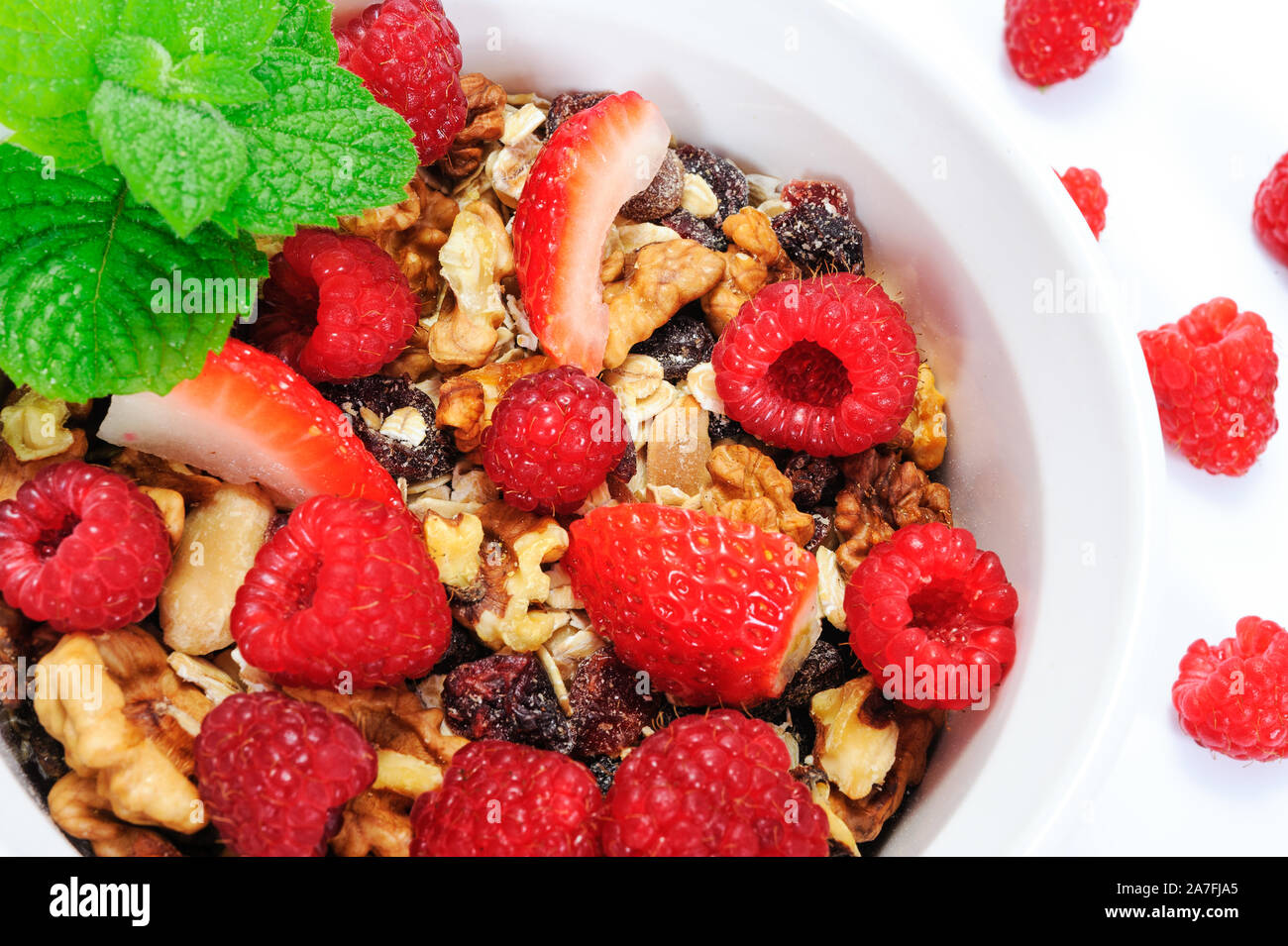 Schale hausgemachter Bio Müsli mit Hafer, Nüsse, Himbeeren und Erdbeeren mit Blättern der Minze in enger gestaltet - Bis Stockfoto