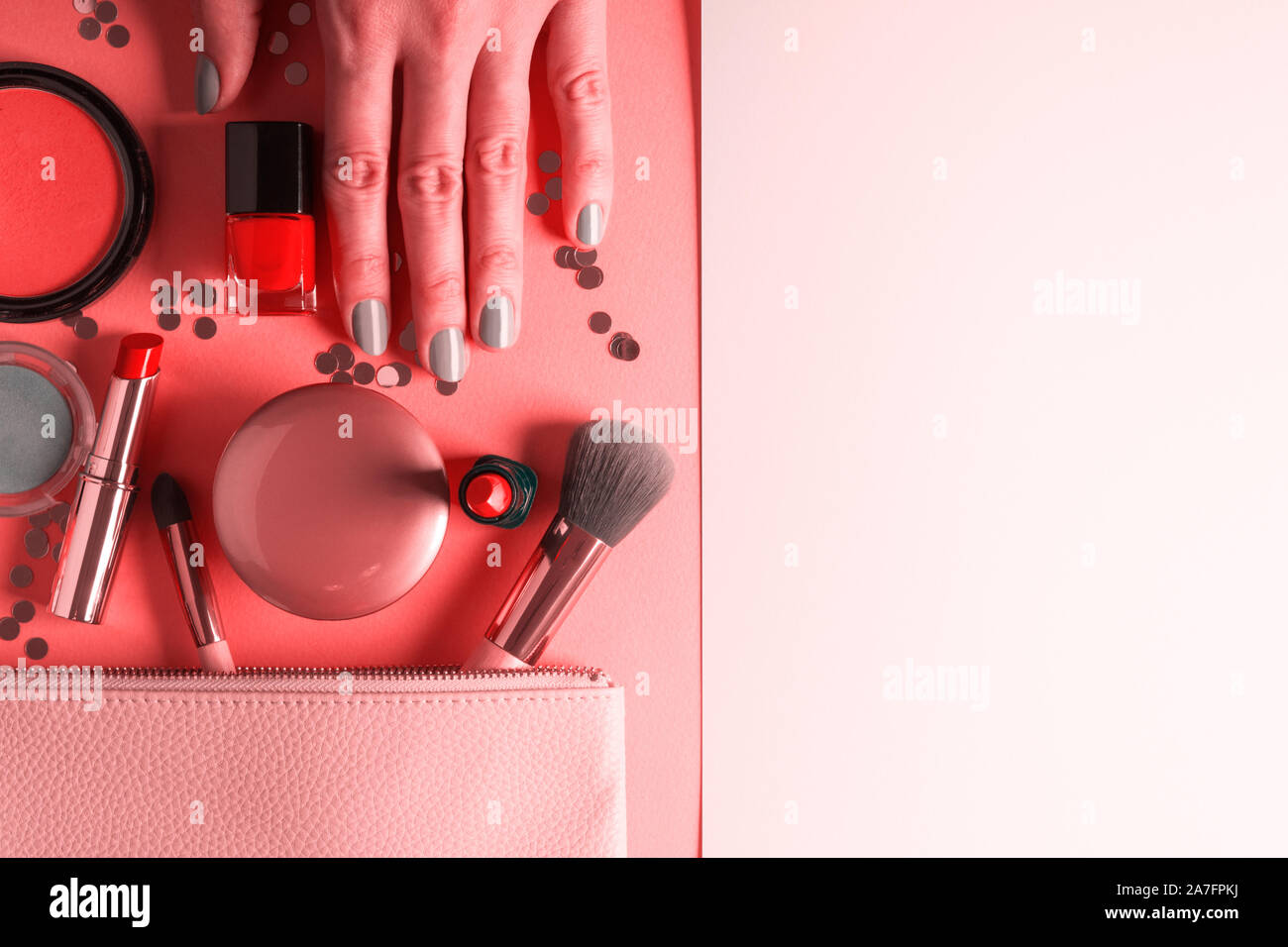 Make up Produkte und Bürsten mit Konfetti auf Coral rosa Hintergrund. Weibliche hand mit silber grau Maniküre. Schönheit flach Stockfoto