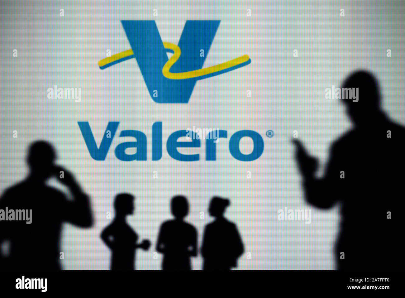 Die Valero Energy Logo ist auf einen LED-Bildschirm im Hintergrund, während eine Silhouette Person ein Smartphone verwendet (nur redaktionelle Nutzung) Stockfoto