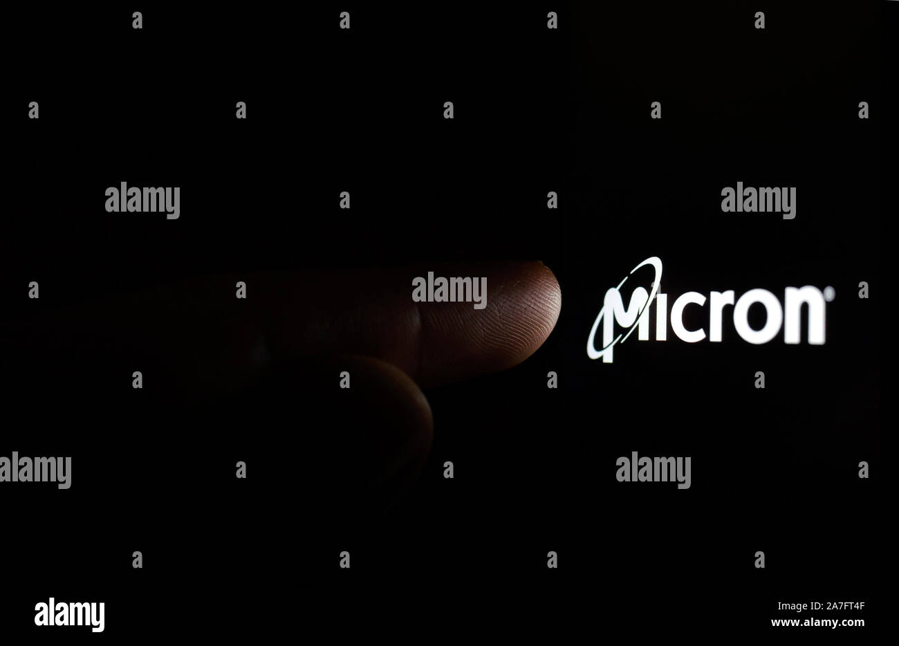 Mikron Logo auf einem Bildschirm des Smartphones in einer dunklen und mit einem Finger berühren. Micron Technology Hersteller von Computer-Speicher, DRAM- und Flashspeicher. Stockfoto