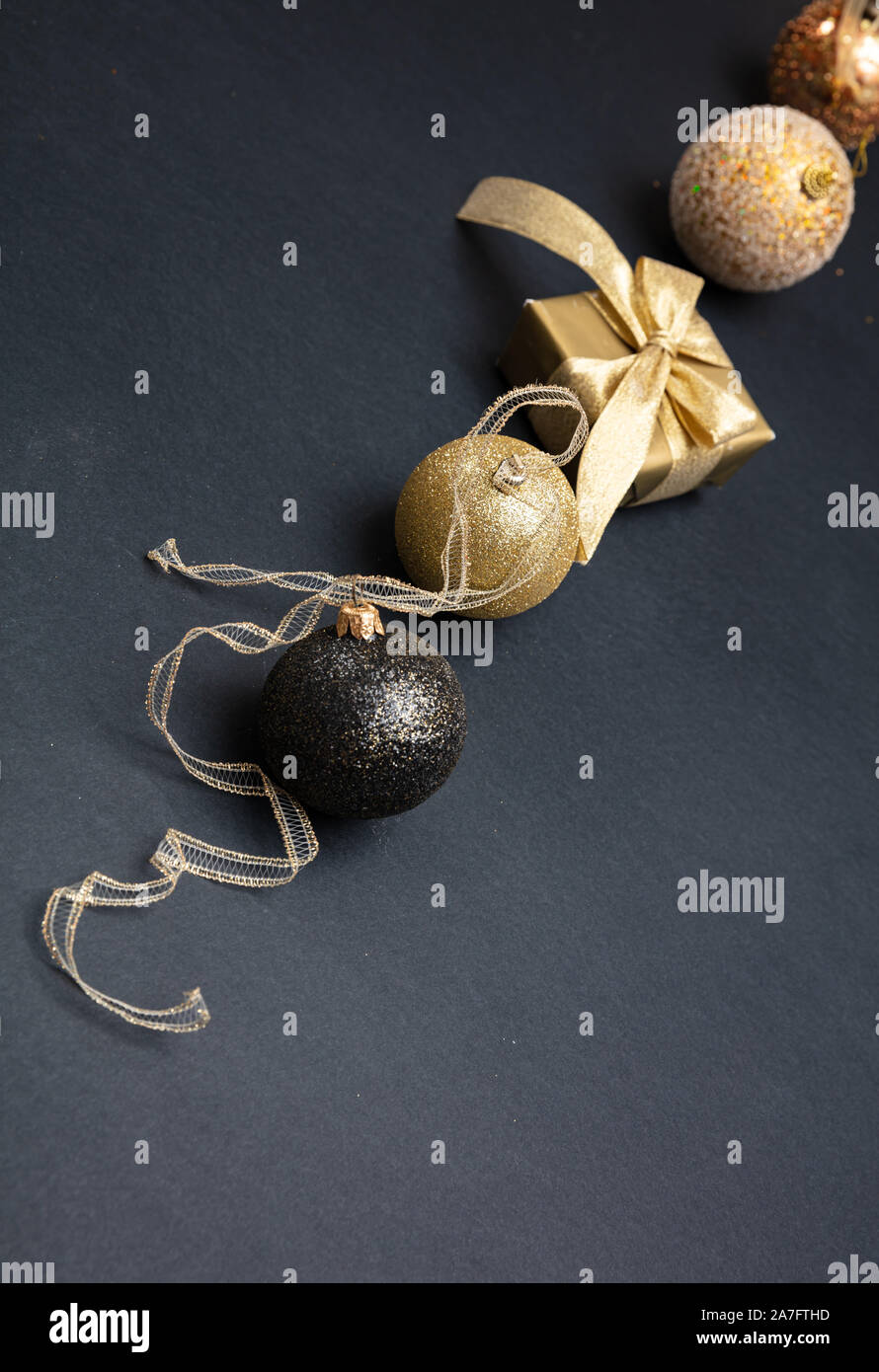 Gold und Schwarz Weihnachten Dekoration. Weihnachten Kugeln und Geschenk bax glänzend gegen dunkelgrauer Hintergrund, kopieren Raum Stockfoto
