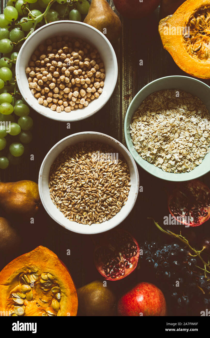 Die herbstlichen Obst, gesundes Müsli Hintergrund, typischen Früchte der herbstlichen Jahreszeit, biologisch angebaute, runden Schalen voller gesunder Getreide Hafer Stockfoto