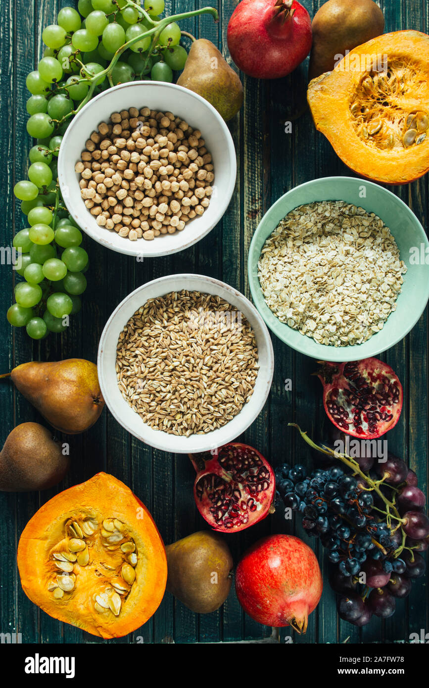 Die herbstlichen Obst, gesundes Müsli Hintergrund, typischen Früchte der herbstlichen Jahreszeit, biologisch angebaute, runden Schalen voller gesunder Getreide Hafer Stockfoto