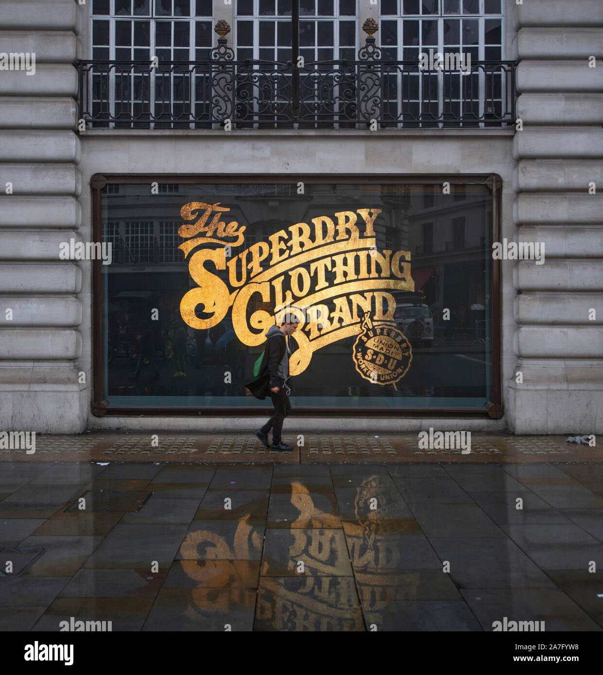 2. November 2019. Superdry store Fenster mit gold Schriftzug auf nasser Fahrbahn im Herbst Wetter widerspiegelt, der Regent Street London, UK. Stockfoto