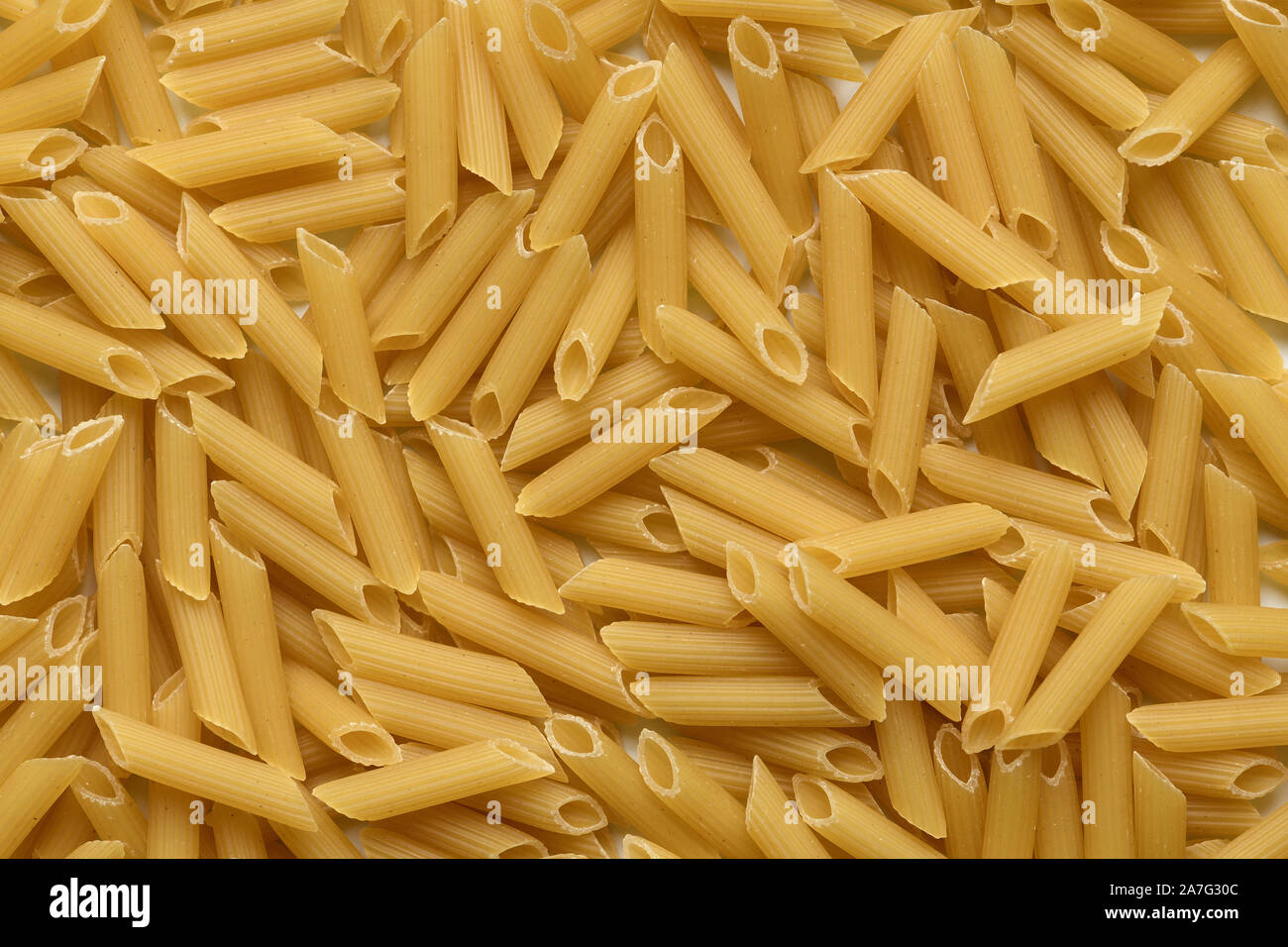 Pasta Penne Rigate Hintergrund, Ansicht von oben. Puristische italienische Küche Thema in hoher Auflösung. Pasta als grundlegender Bestandteil in der Rezeptur. Stockfoto