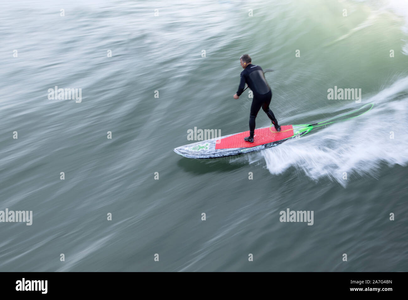 Ein Stand-up Paddle boarder reitet eine Welle in Camborne, Cornwall Stockfoto