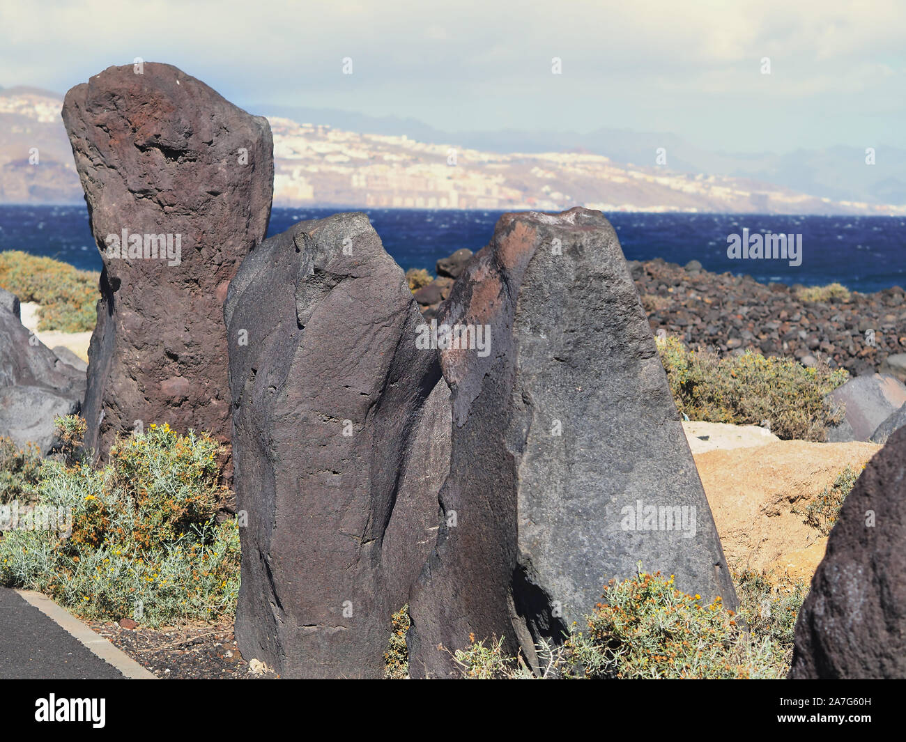 Sehr groß, aufrecht stehend Grau-Lilane lava Steine am Straßenrand neben einander vor der Atlantikküste auf der Insel Teneriffa. In der Ferne die Stockfoto
