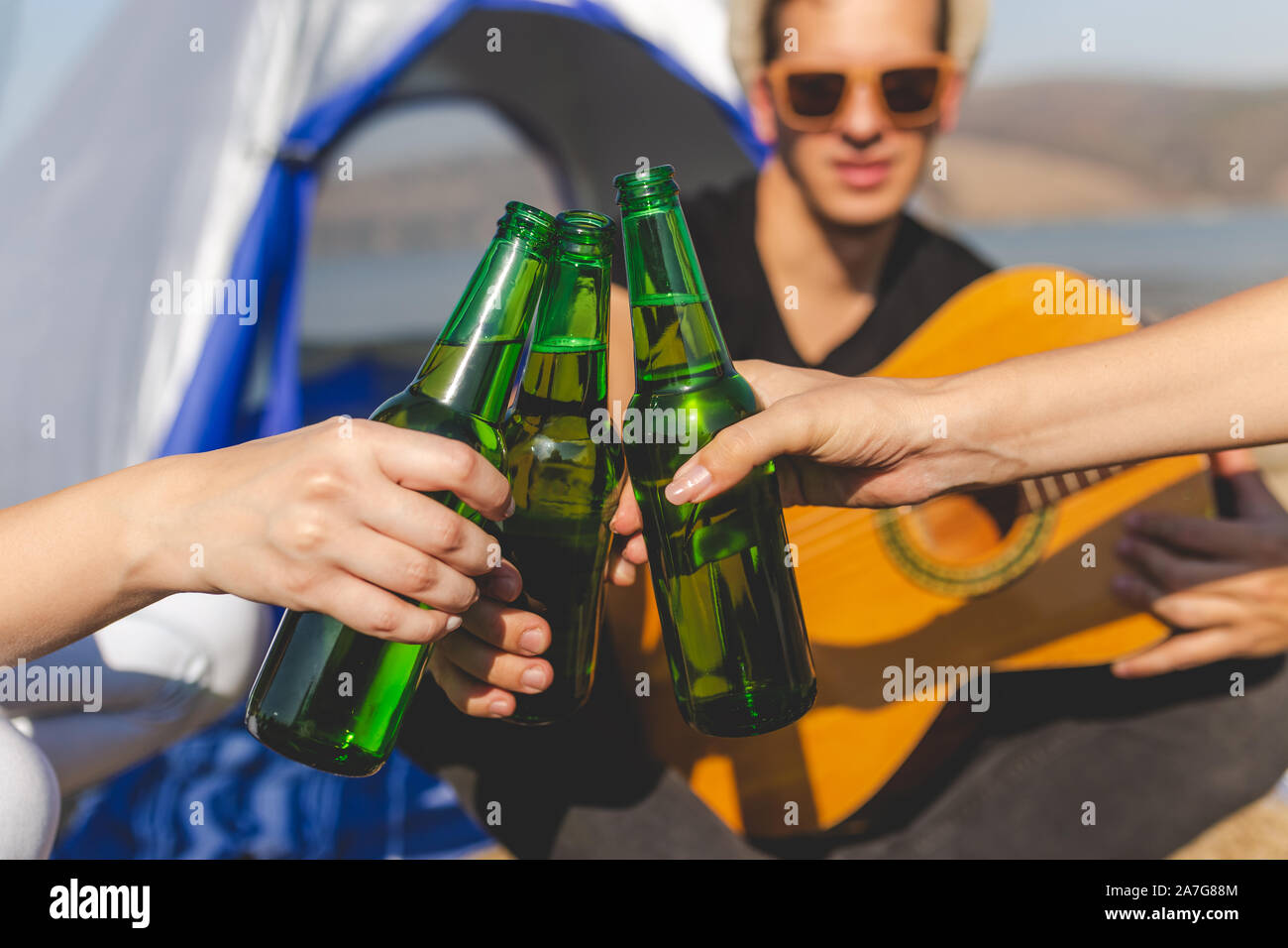 Freunde klirrenden Flaschen Bier am Strand camping Picknick. Stockfoto
