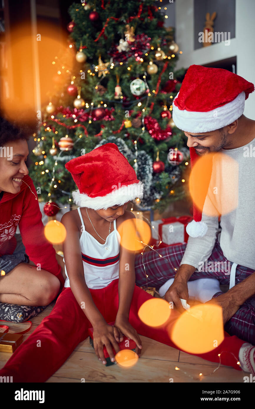 Glückliche Eltern mit Tochter vor geschmückten Weihnachtsbaum zu Hause viel Spaß Stockfoto