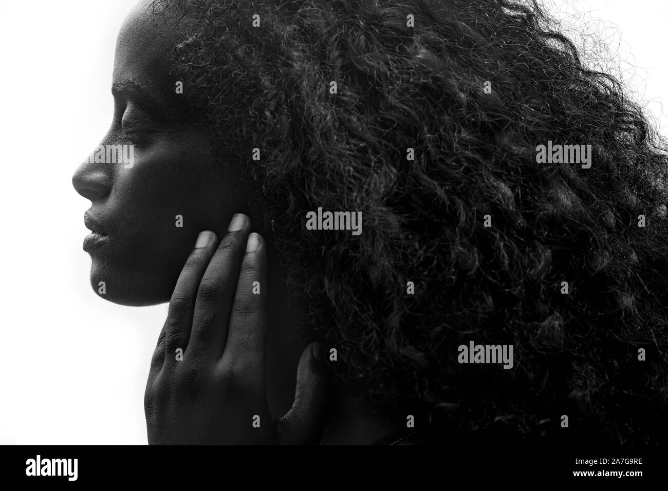 Profil Portrait von eine schöne junge afrikanische Frau mit dicken lockigen Haar sanft ihr Gesicht zu berühren, auf weißem Hintergrund Stockfoto