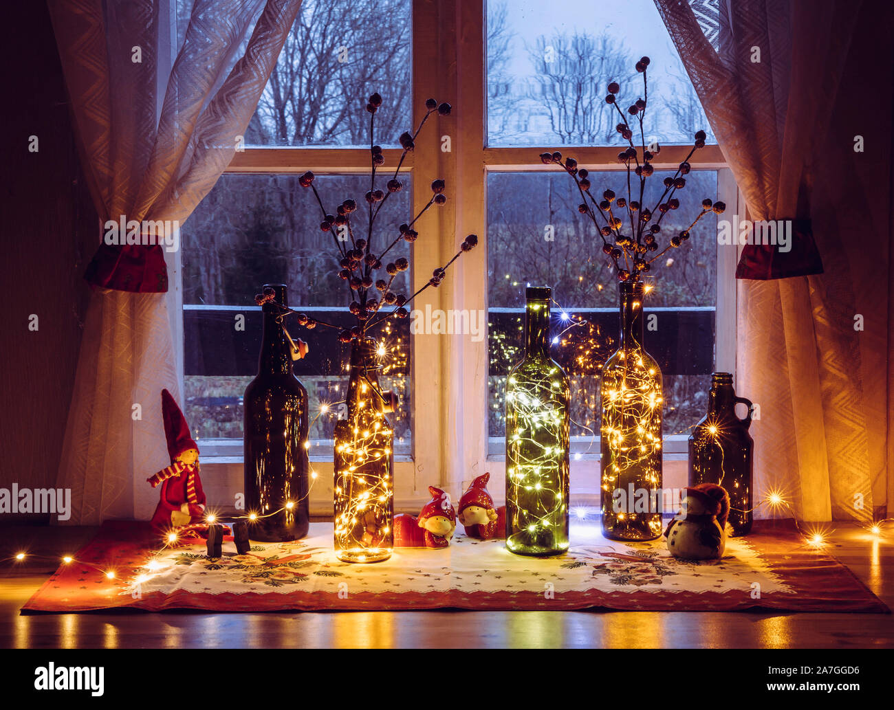 Süß und warm Weihnachten Dekoration mit Vintage Flaschen Bier und Wein Flaschen gefüllt mit Micro party Beleuchtung LED, hinter dem Fenster ist auf dem Land Stockfoto