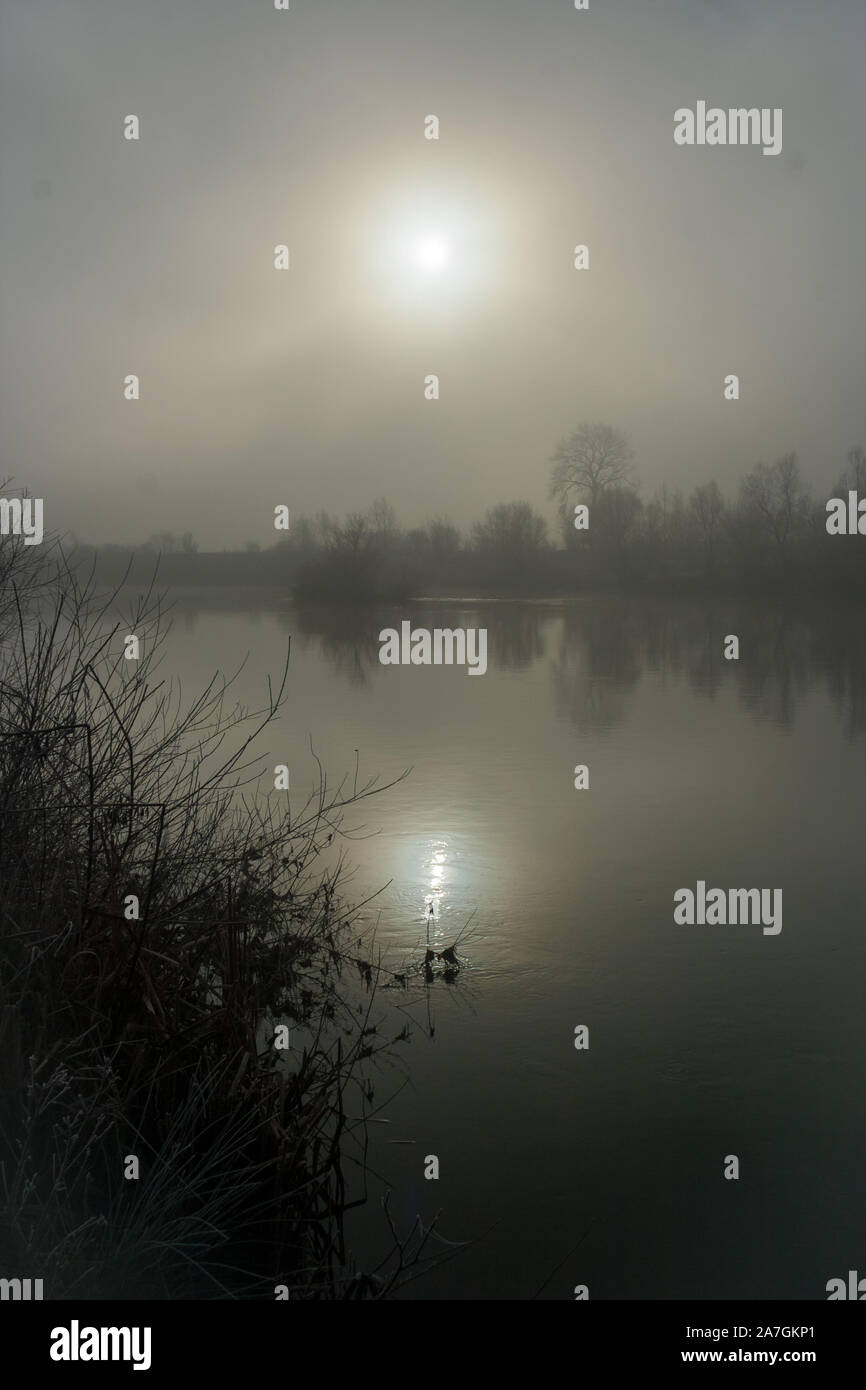 Die Reflexion der Sonne im Wasser eines Flusses in Siebenbürgen, Rumänien auf einem nebligen Winter morgen Stockfoto