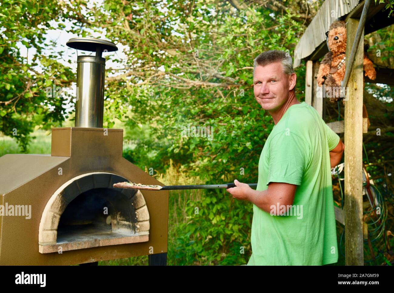 Mann kochen handwerklichen Pizza draußen in einem Holzofen Forno Bravo Backofen, mit Zutaten aus biologischem Anbau am Inn Serendipity, Browntown, Wisconsin, USA Stockfoto