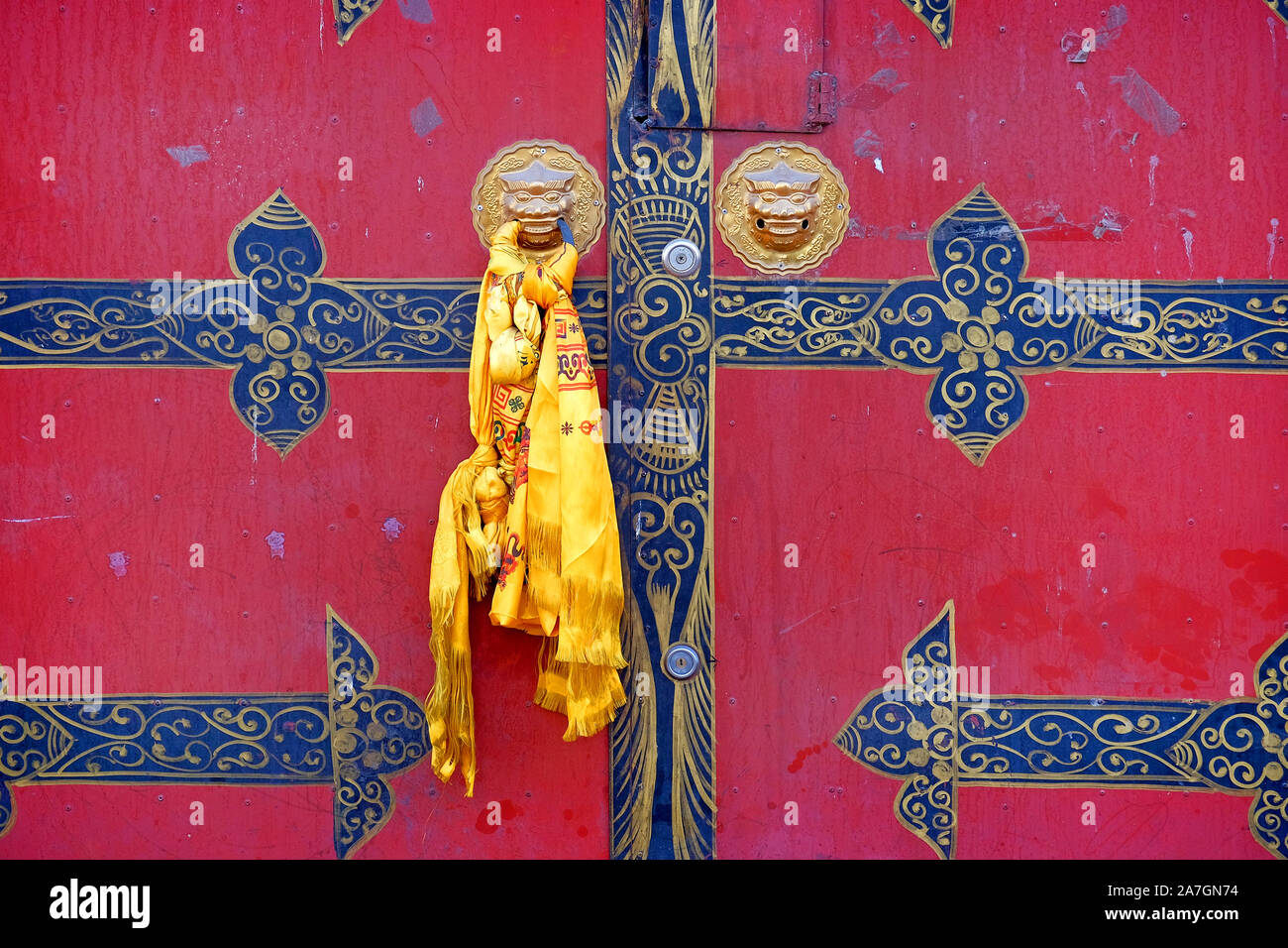 Traditionelle Tibetische gelben Schal auf eine alte rote Tür mit goldenen Motiven, in Lhasa. Stockfoto