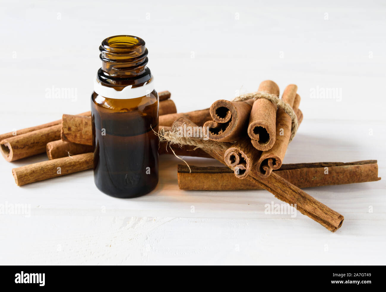 Nahaufnahme, Zimtstangen und Zimt Öl in eine Flasche auf einem weißen Holz- Hintergrund Stockfoto