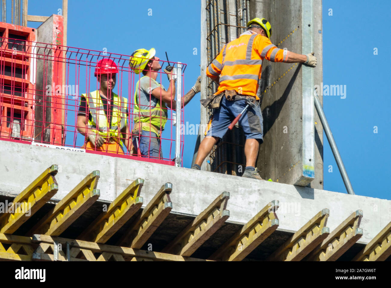 Drei Bauarbeiter setzen den Betonblock von Kranarbeitern präzise ab Baustelle Betonbauarbeiter Stockfoto