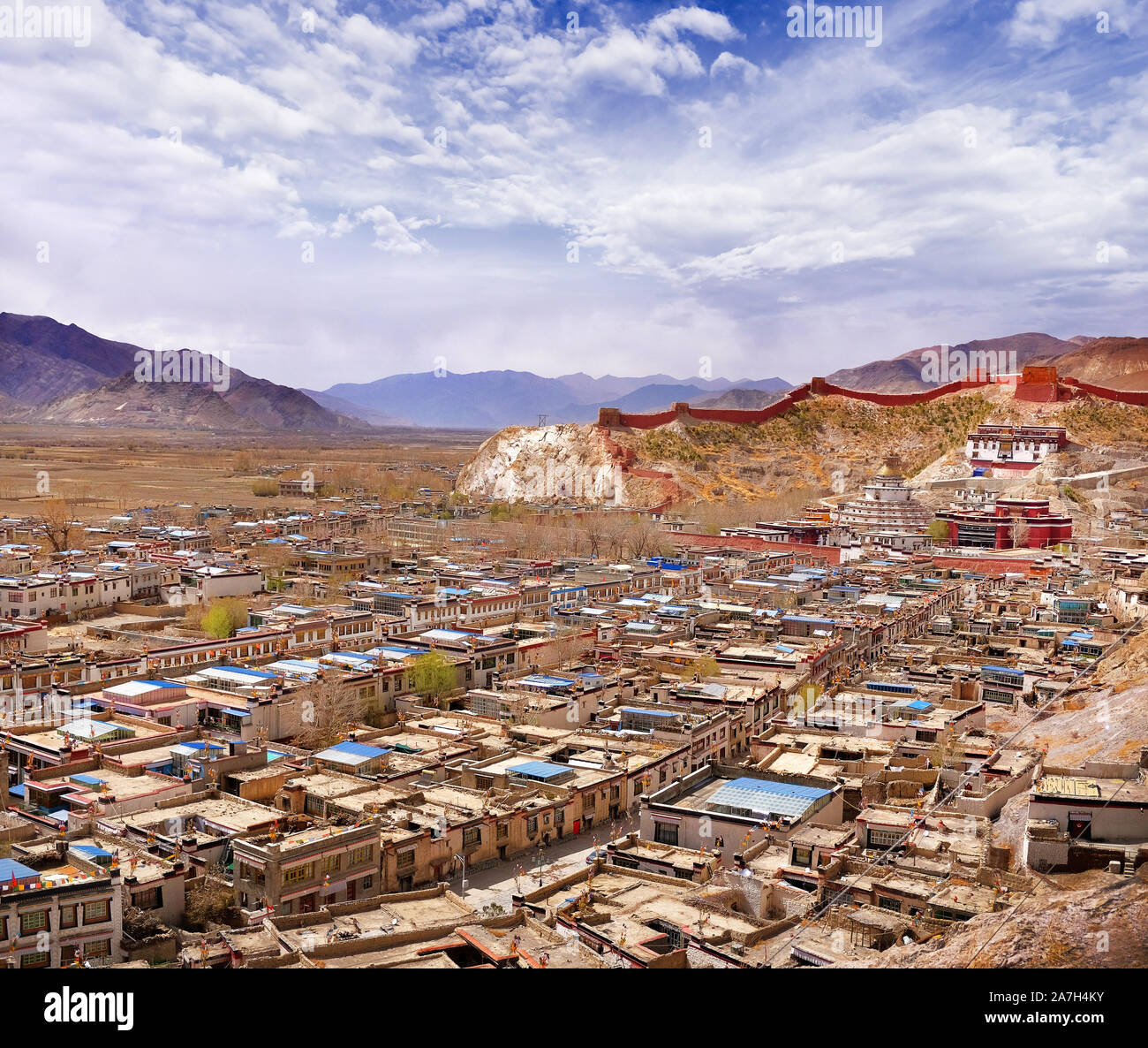 Ansicht der Traditionellen Tibetischen Dorf durch die Berge des Himalaja, gegen ein blauer Himmel mit weißen Wolken umgeben. Stockfoto