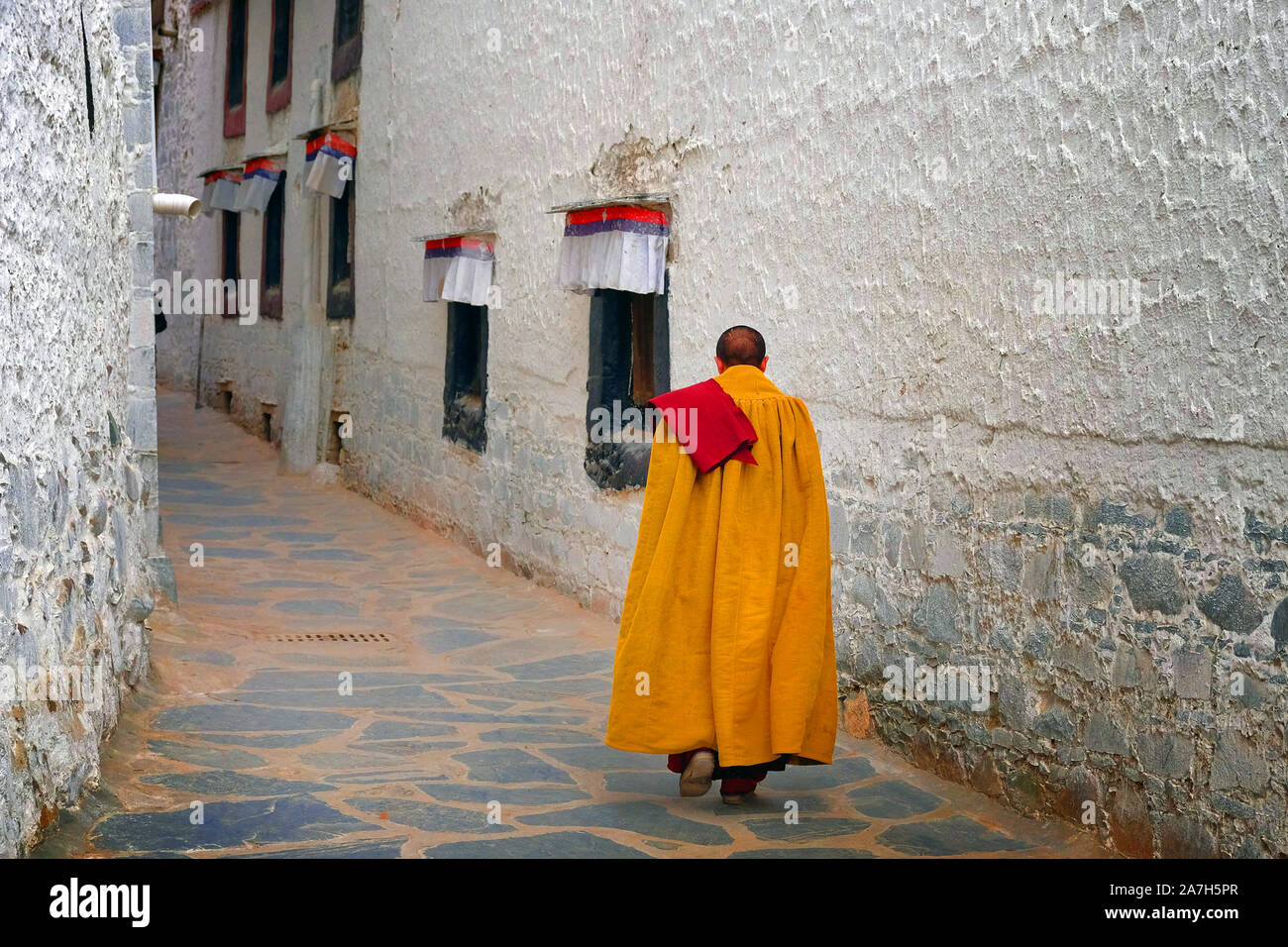 Der tibetische Mönch, in Gelb gekleidet, Wandern auf den Straßen der Tashilhunpo Kloster in Shigatse. Stockfoto