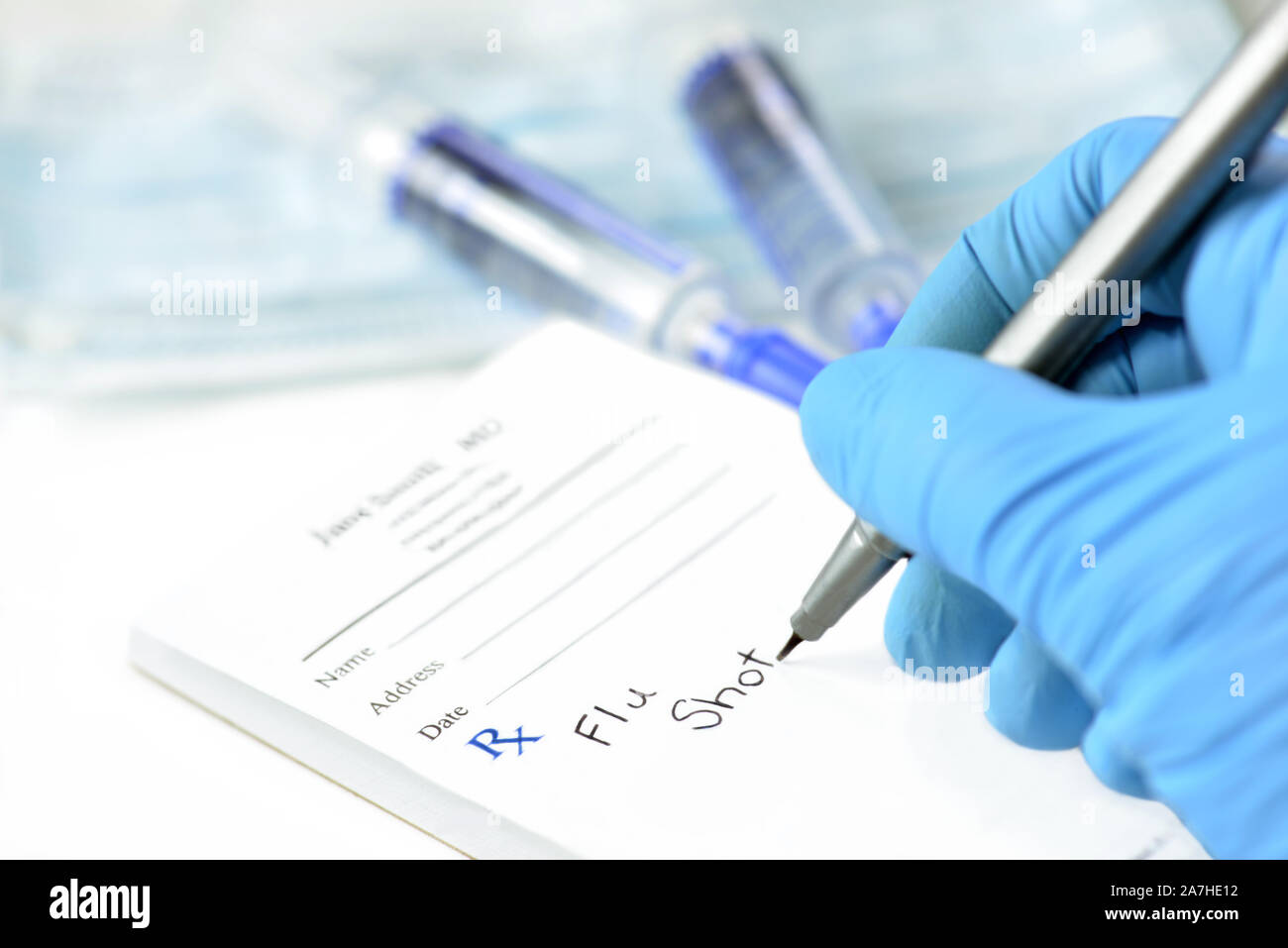 Behandschuhte hand Doctor's schreibt Rezept für Grippe Impfstoff auf verordnungsformular. Stockfoto