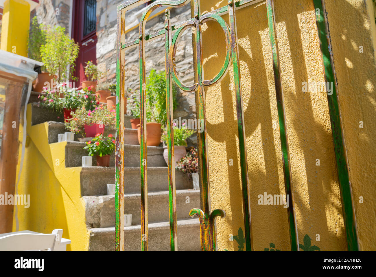 Schritte in kleinen Eingang Innenhof hinter gelben und grünen schmiedeeisernes Tor. Stockfoto