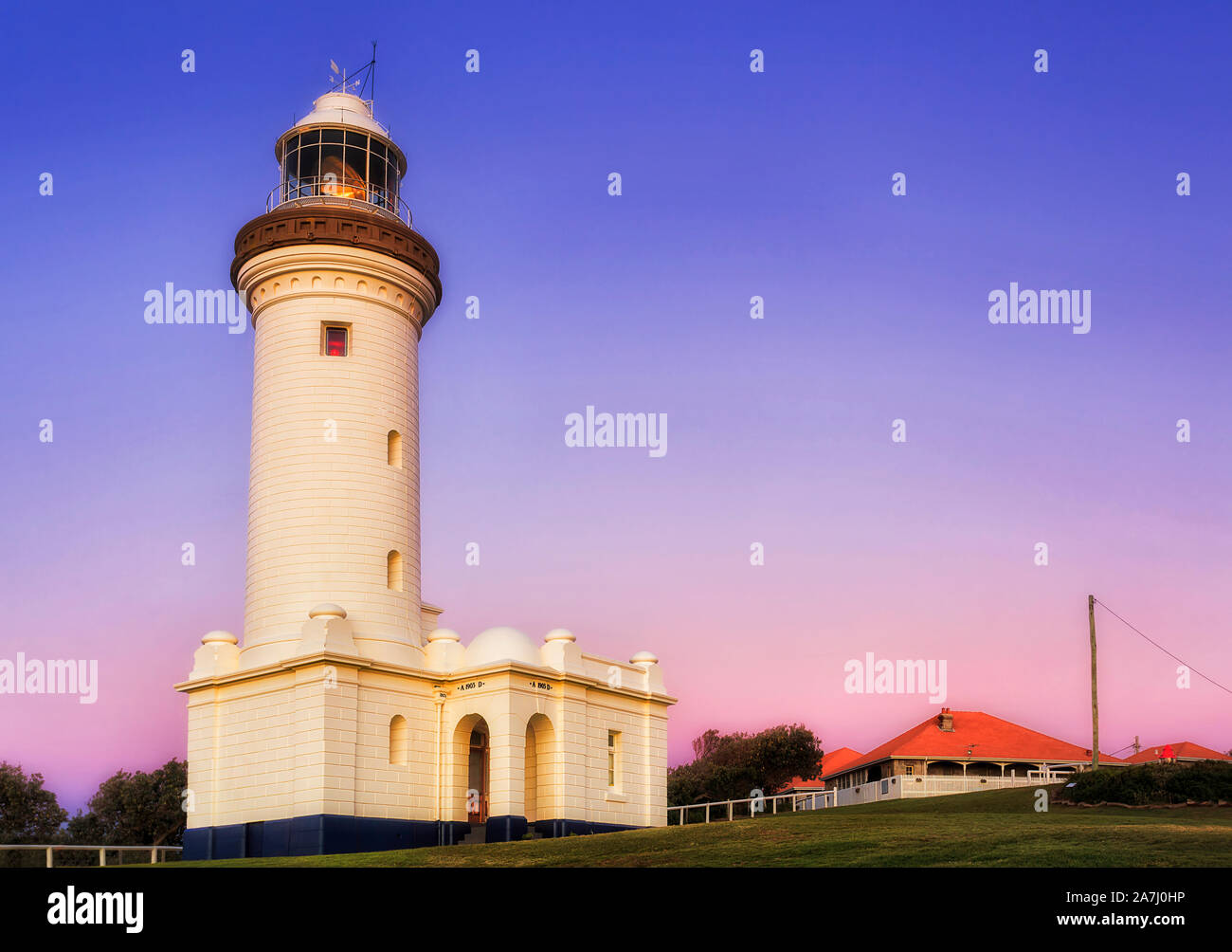 Weißer Stein Leuchtturm auf Norah Head von Australian Pacific Central Coast bei Sonnenaufgang gegen blau und rosa Himmel mit Beleuchtung Reflektor spiegeln Drehen einer Stockfoto
