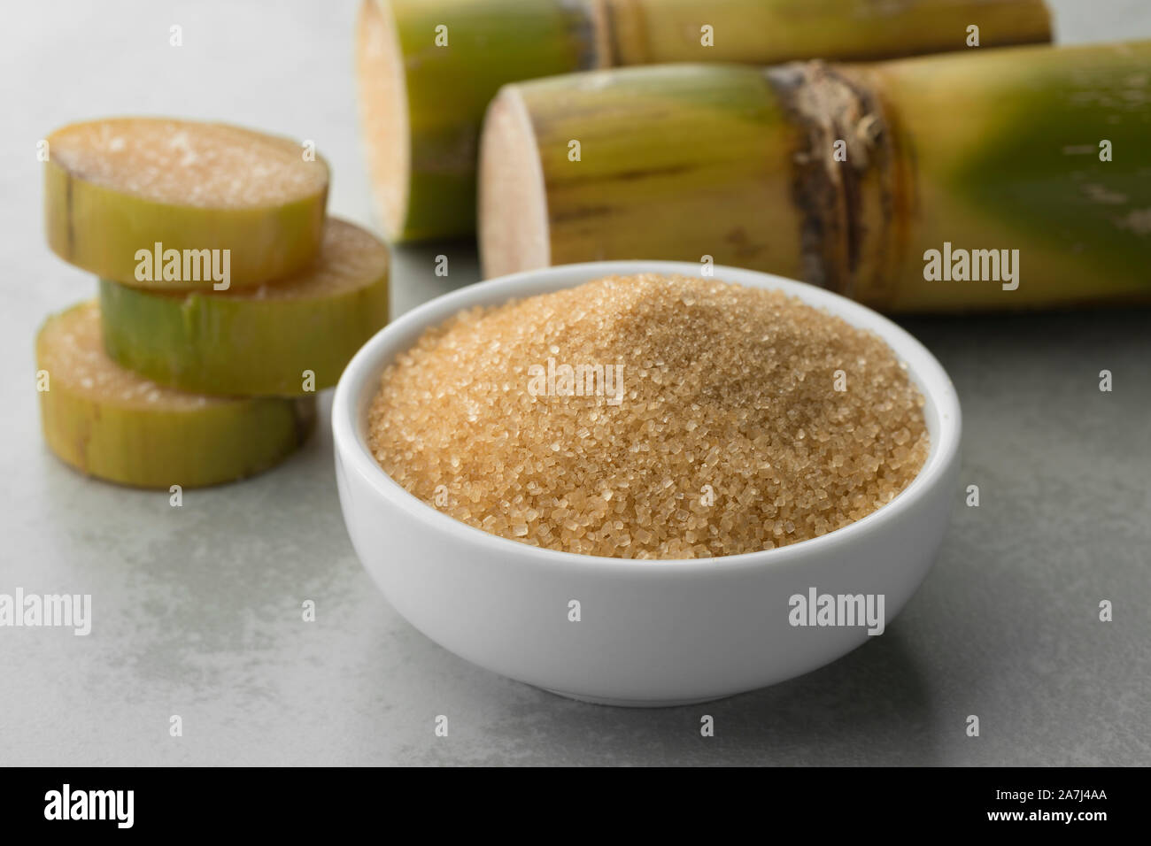 Schüssel mit Rohrzucker und frisches Zuckerrohr im Hintergrund Stockfoto