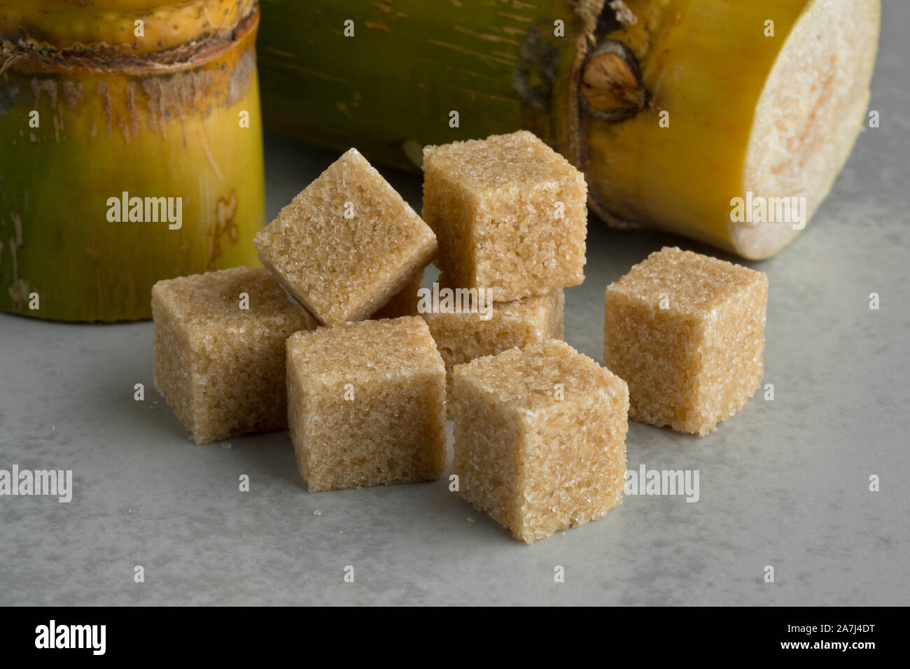 Rohrzucker Würfel und frisches Zuckerrohr im Hintergrund Stockfoto