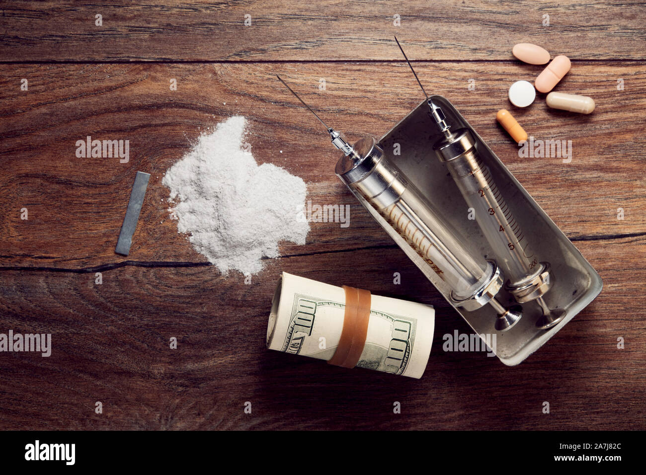 Vintage spritzen, Kokain, Pillen und gerollten Dollarnoten auf hölzernen Tisch. Konzept der Drogenabhängigkeit und des Drogenhandels. Stockfoto
