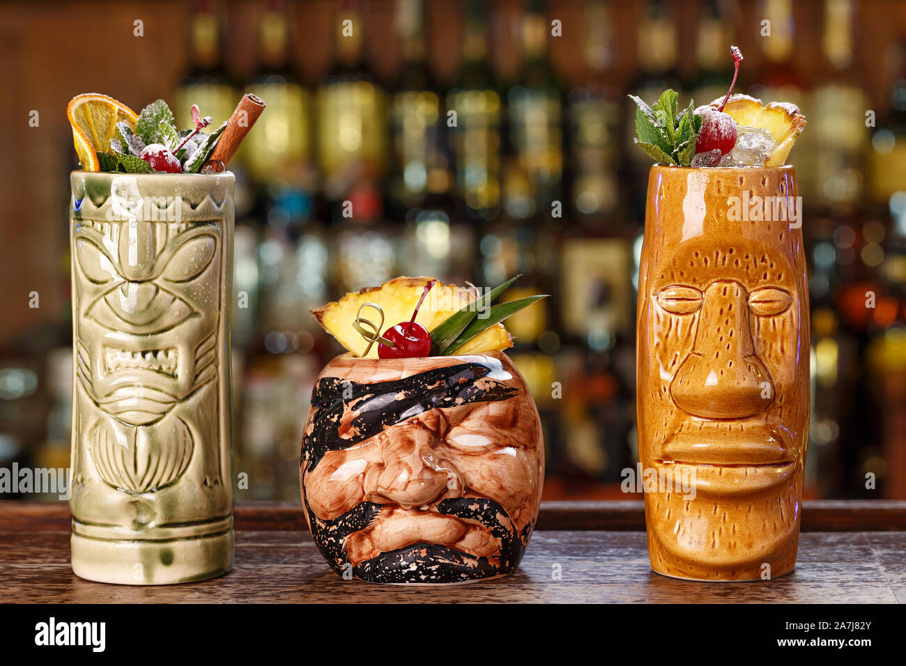 Satz von drei tropische Cocktails in Tiki Gläser in einem Nachtclub auf dem Hintergrund einer Theke. Lange alkoholische Cocktails mit Eis, Rum und verschiedene Stockfoto