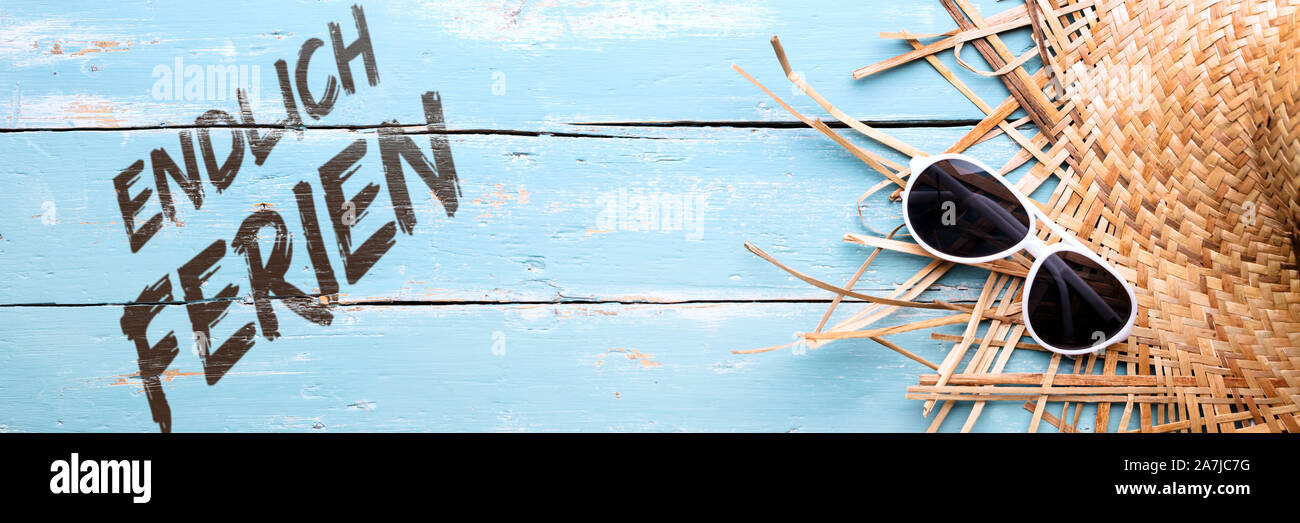 Sonnenbrille und Sonnenhut auf Blau Holztisch, deutsche Text endlich Ferien, endlich Ferien bedeutet Stockfoto