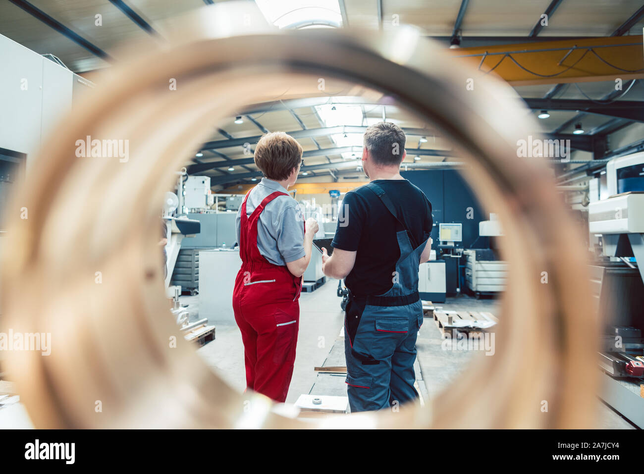 Arbeitnehmer stehen auf der Fabrik durch ein Werkstück gesehen Stockfoto