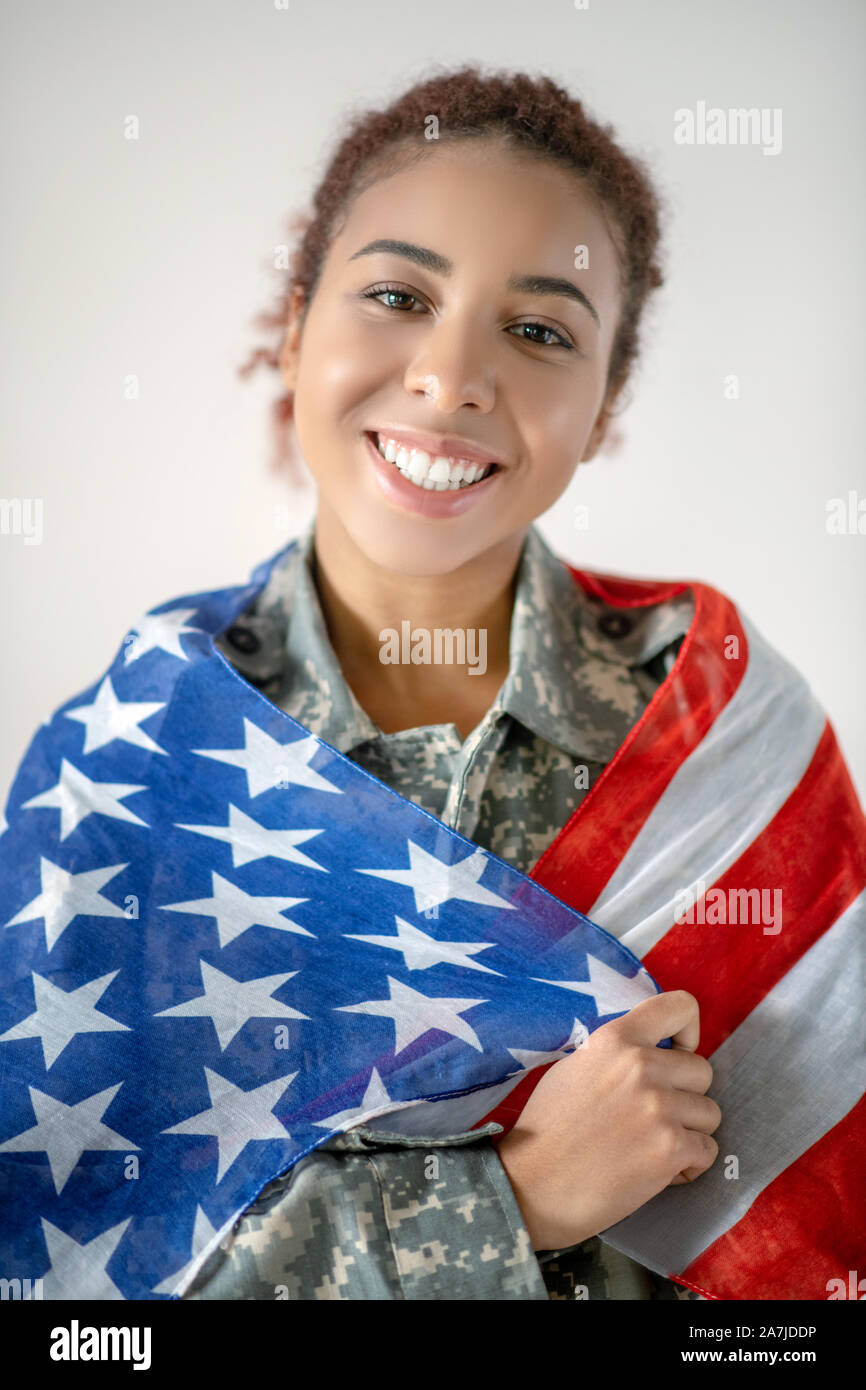 Junge servicewoman tragen militärische woman holding Flag Stockfoto