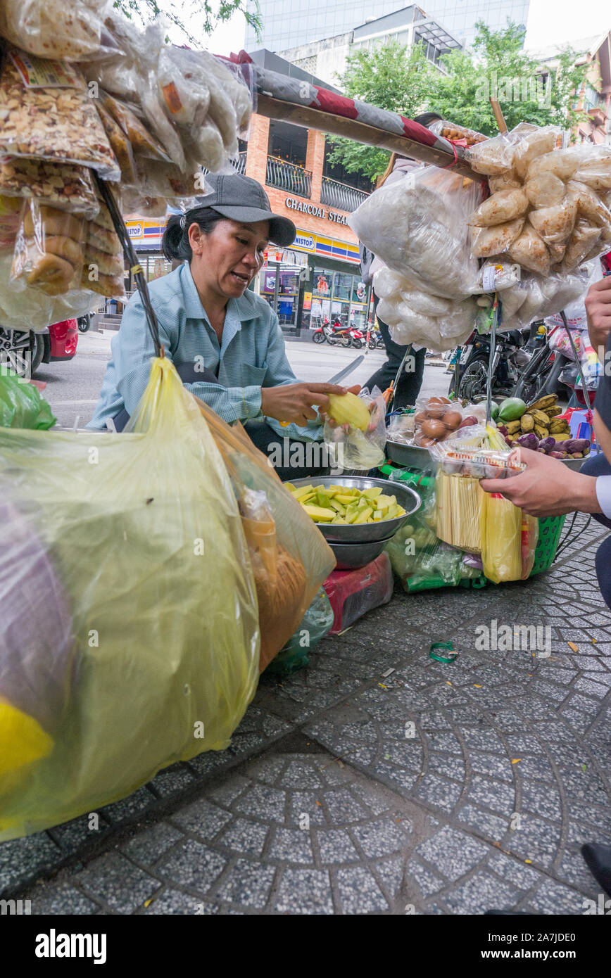 Close-up Street Food Anbieter schneiden Obst und Verkauf an Mitarbeiter im Büro für das Mittagessen an Saigon Bürgersteig. Stockfoto