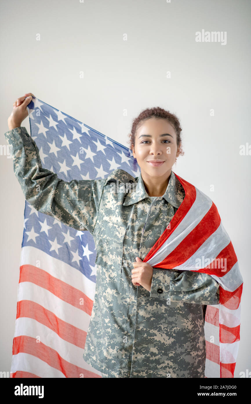 Patriotische junge hübsche servicewoman Holding National Flagge Stockfoto