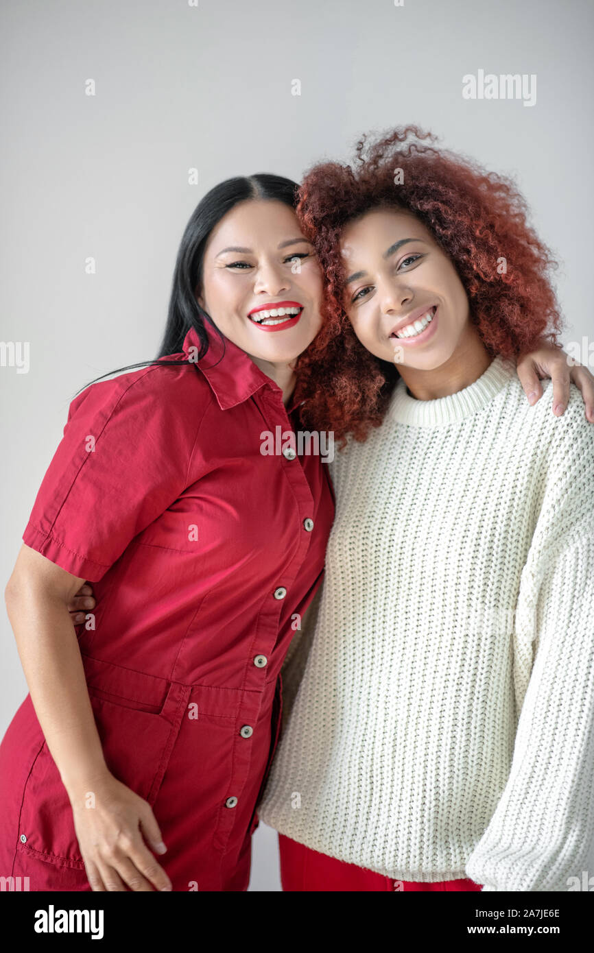 Asiatische strahlende Frau ihren Curly ansprechende Freund umarmen Stockfoto