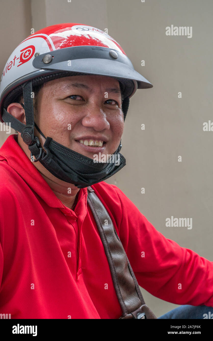 Lächelnd Portrait von GoViet Motorrad Taxifahrer in Ho Chi Minh City Vietnam. Tragen helle rote GoViet Jacken und glänzend rot Helme. Stockfoto
