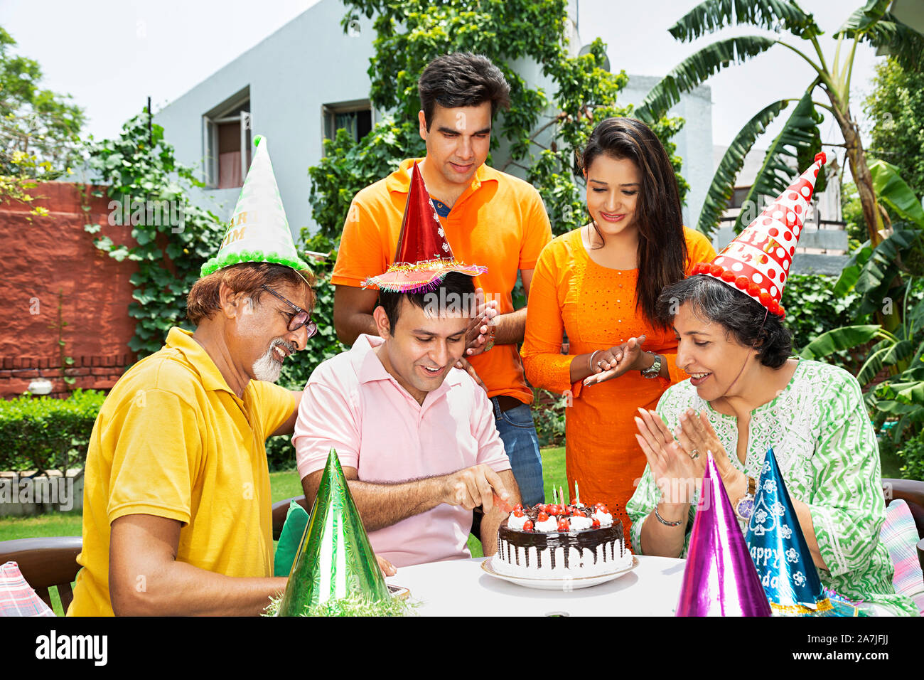 Gerne indische Familie Geburtstagsfeier und Sohn schneiden Geburtstagstorte im Garten ihres Hauses Stockfoto